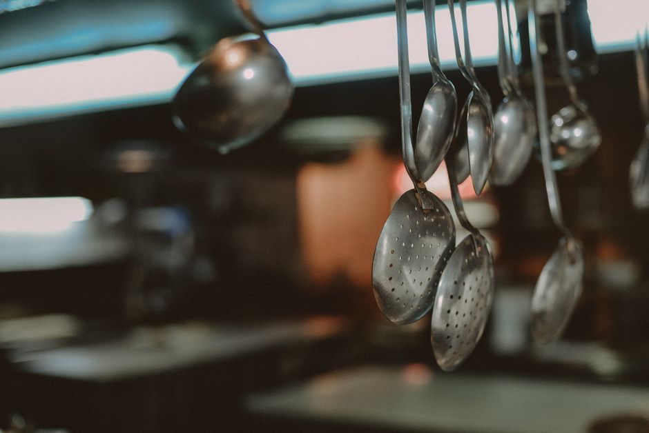 Essentiële koel- en keukenapparatuur in een professionele horecakeuken, zoals koeltoonbanken en espressomachines.